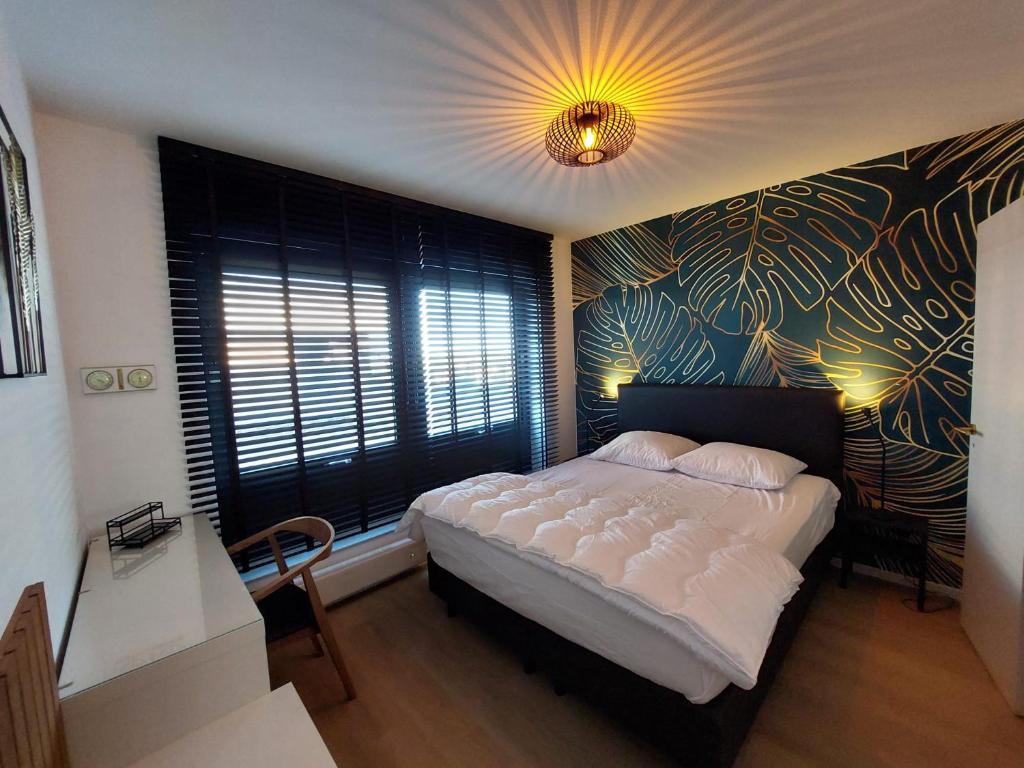 - une chambre avec un grand lit blanc et une fresque murale dans l'établissement The Vans, à La Panne