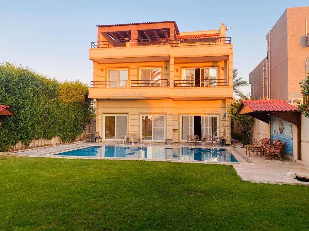 a house with a swimming pool in front of a yard at Lovely Villa 5- bedroom with Overflow Pool with Nice Garden at Green Oasis Resort in Alexandria