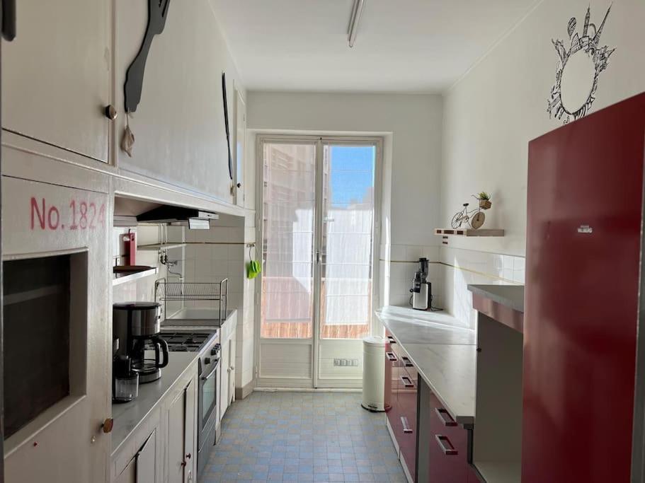 マルセイユにあるAppartement vieux portの白いキャビネットと大きな窓付きのキッチン