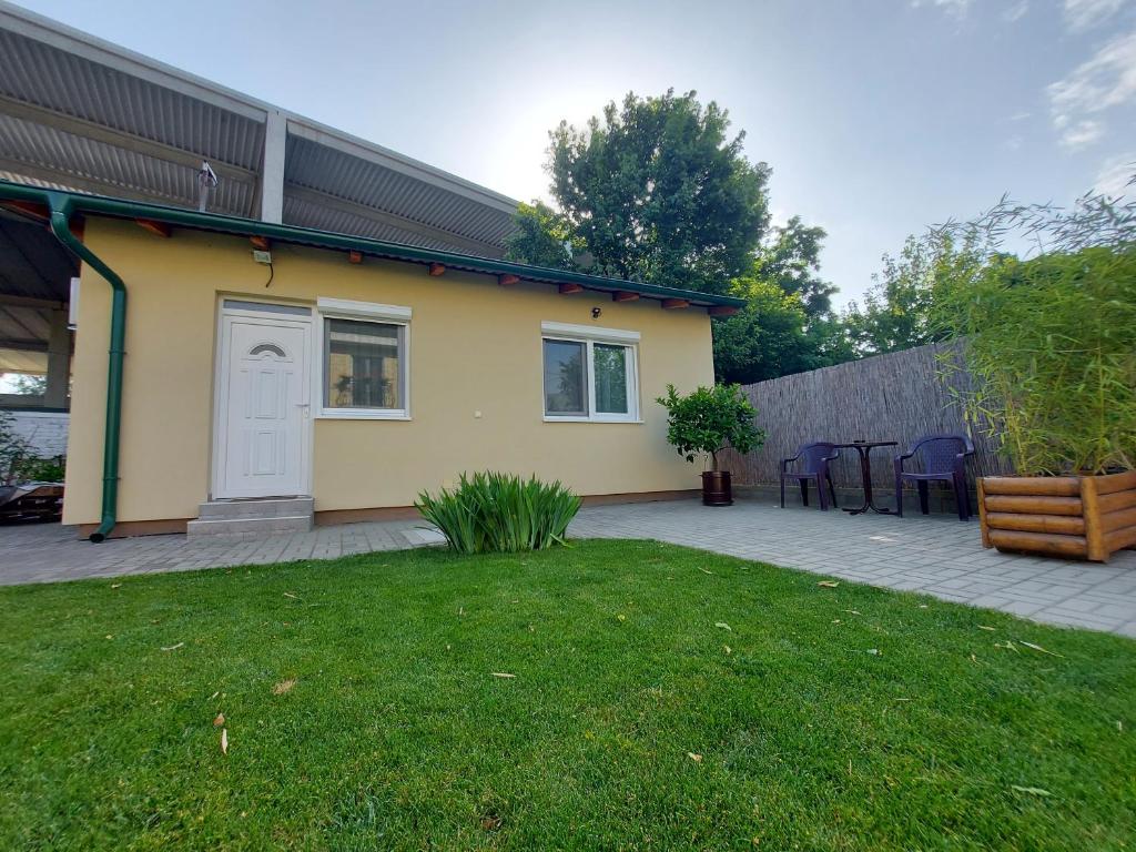 a yellow house with a patio and a yard at Garden House Novi Sad in Novi Sad