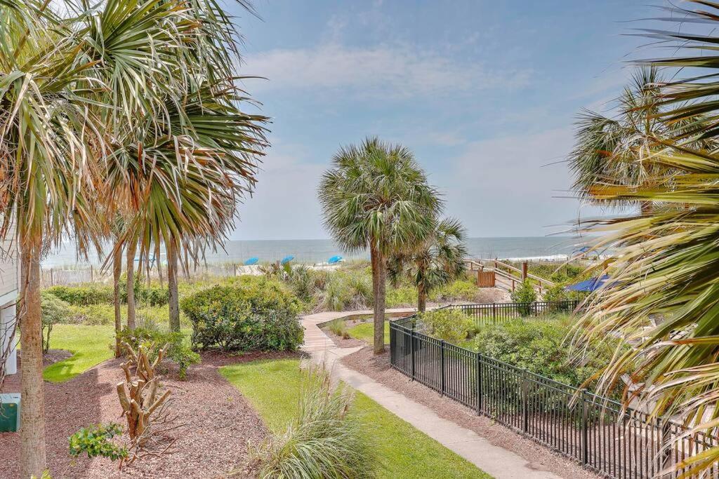 a walkway through a park with palm trees and the ocean at New Listing! Seagrove Villa 3A - Luxurious Ocean View! in Isle of Palms