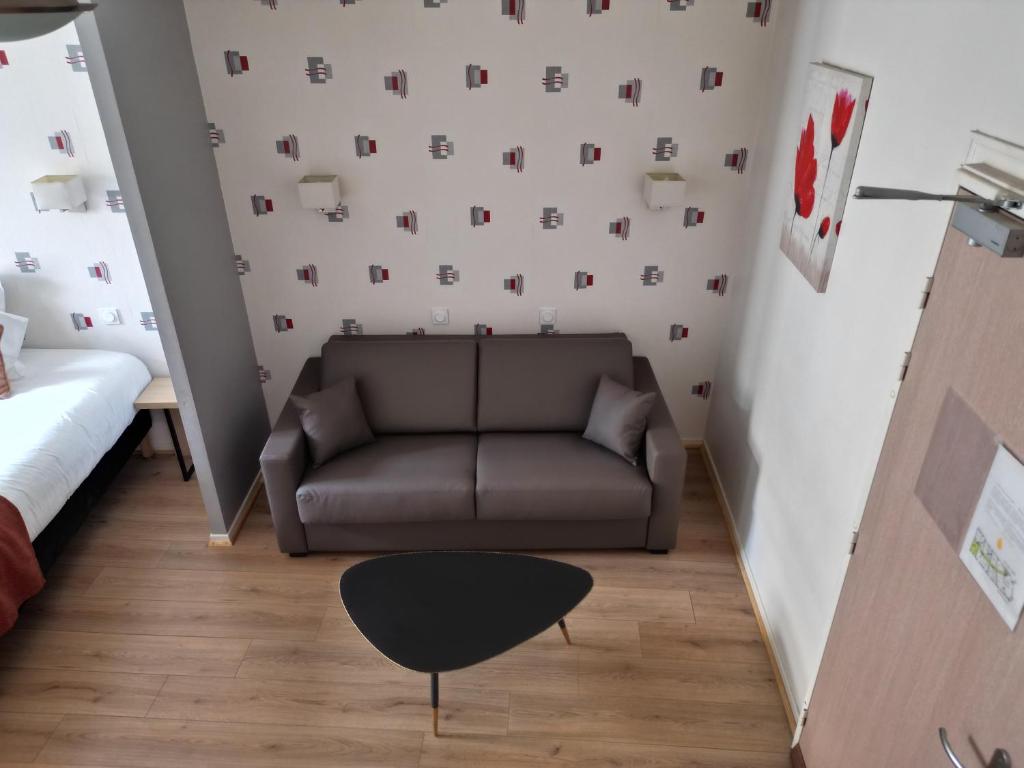 a living room with a couch and a chair at Hôtel les Platanes in Villeneuve-sur-Lot