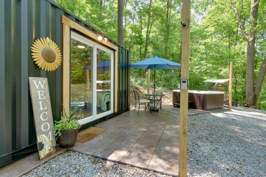 a screened in porch of a house with an umbrella at Tiny Home with Hot Tub By Mohican State Park! in Loudonville
