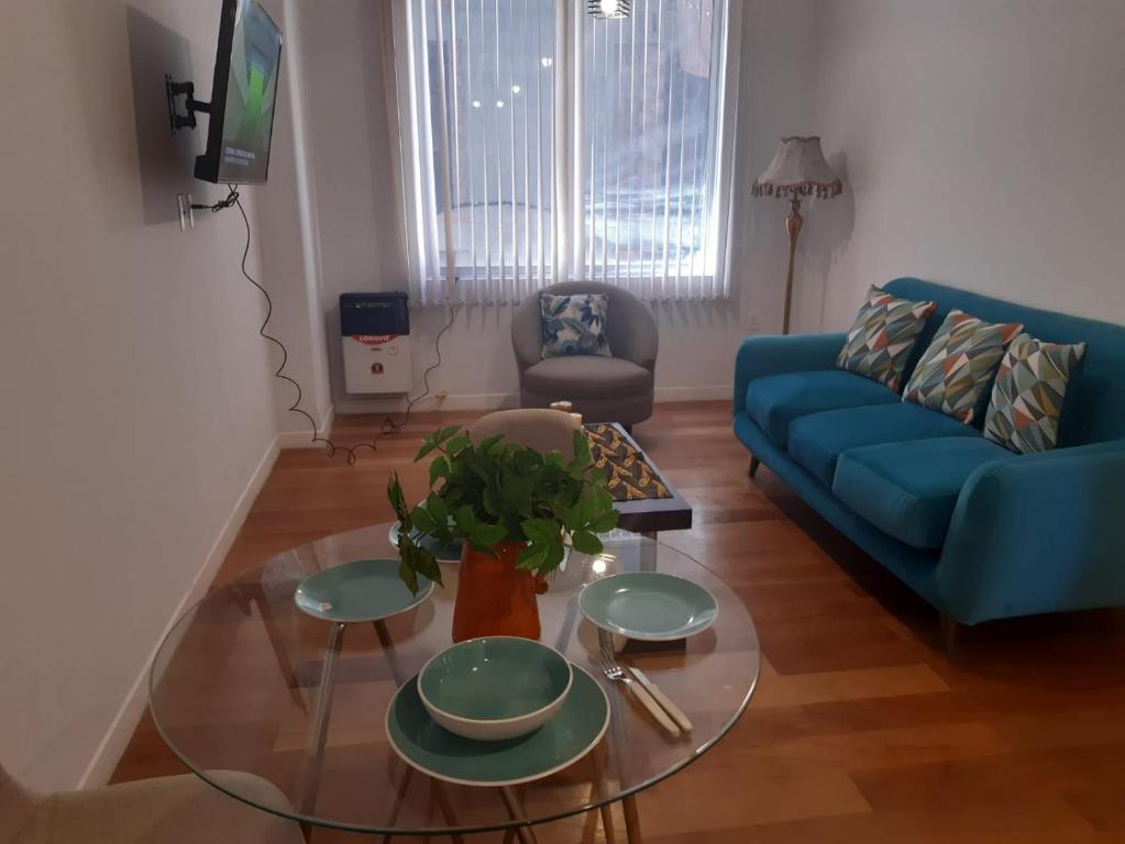 a living room with a blue couch and a glass table at Céntrico y Cómodo departamento VIP in La Paz
