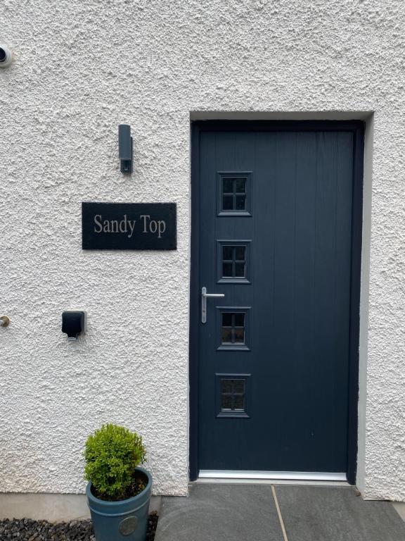 une porte de garage bleue avec un panneau indiquant le haut sableux dans l'établissement Sandy Top, à Saint Abbs