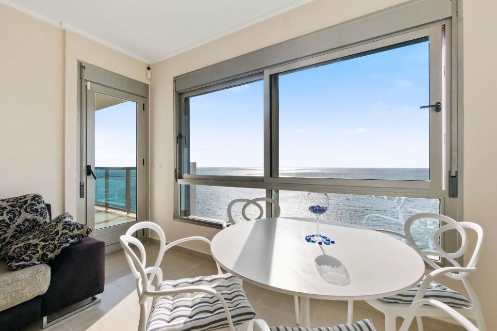 een witte tafel en stoelen in een kamer met ramen bij My seaviews - Euromarina Towers La Manga in La Manga del Mar Menor