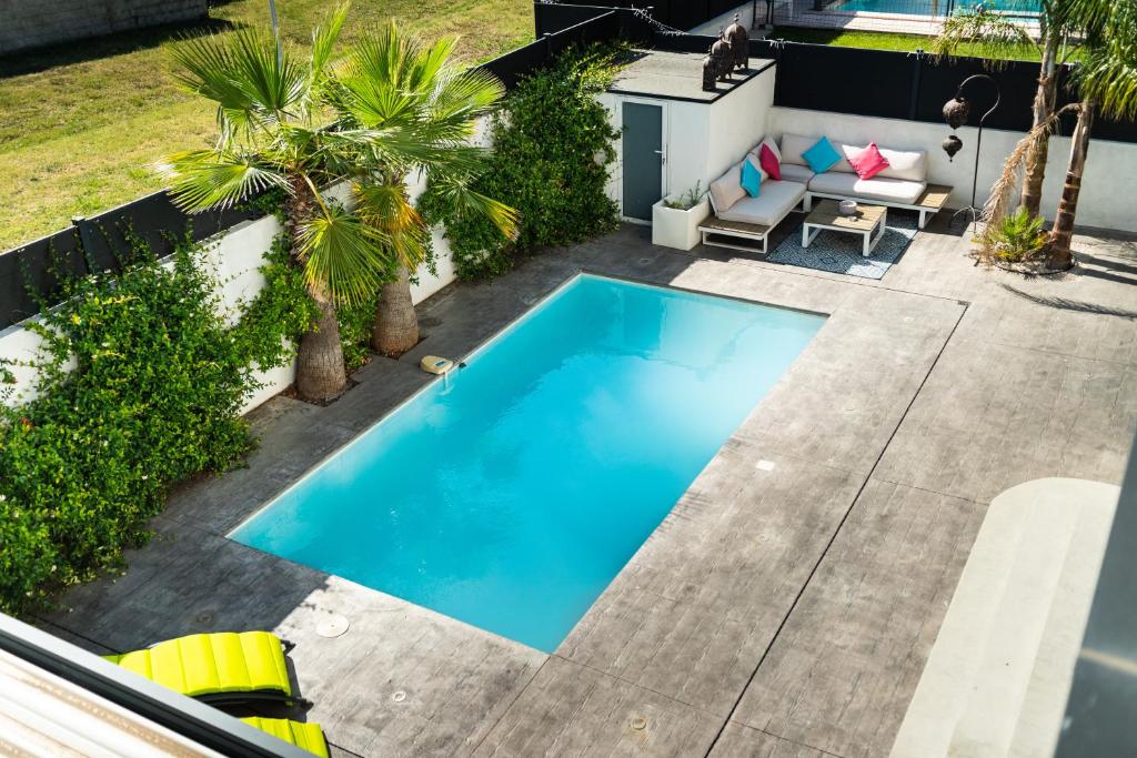 uma vista sobre uma piscina num quintal com palmeiras em SUD VILLA DE LUXE - PLAGES - PISCINE - JACUZZI - Jeux Olympiques 2024 em Lattes