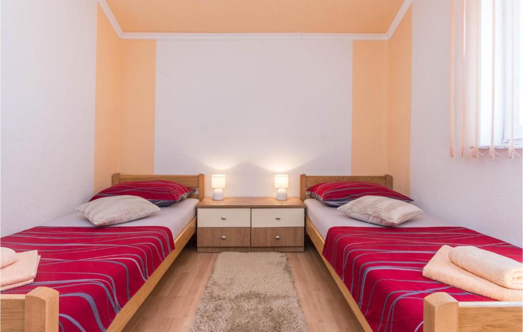 two beds in a small room with red sheets at 4 Bedroom Amazing Home In Miranje in Miranje