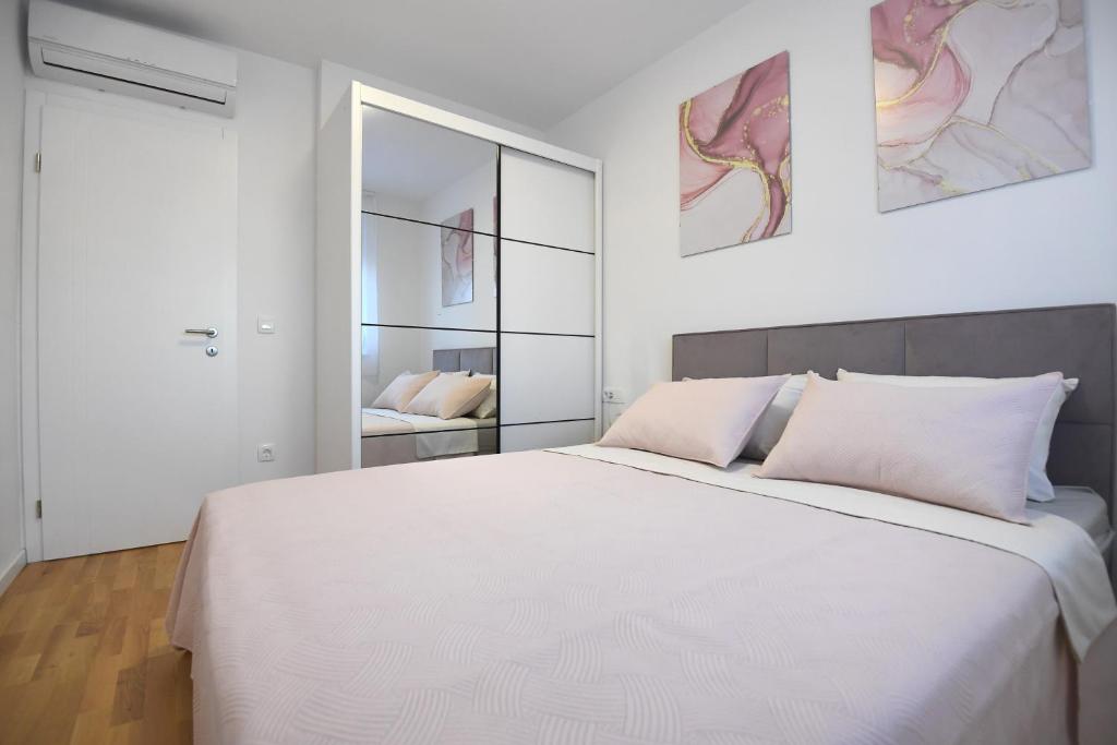 een slaapkamer met een groot wit bed en een spiegel bij Garden apartment Leoma with free parking! in Zadar
