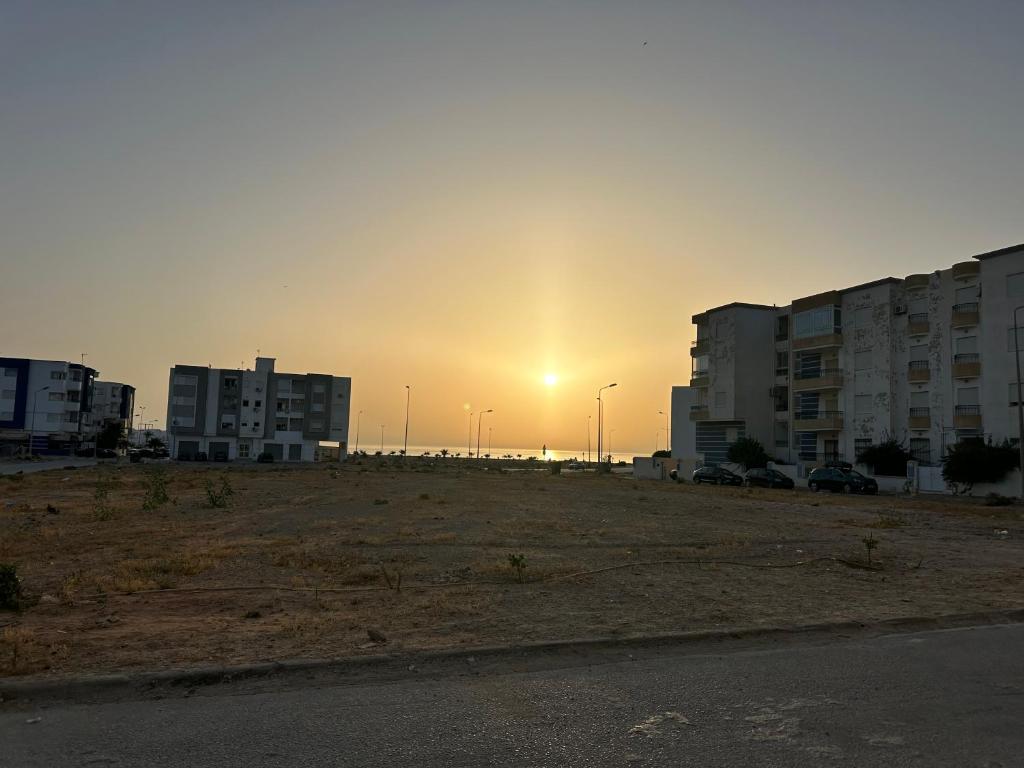 un parcheggio vuoto con il sole che tramonta dietro gli edifici di Sousse Beach luxe a Harqalah