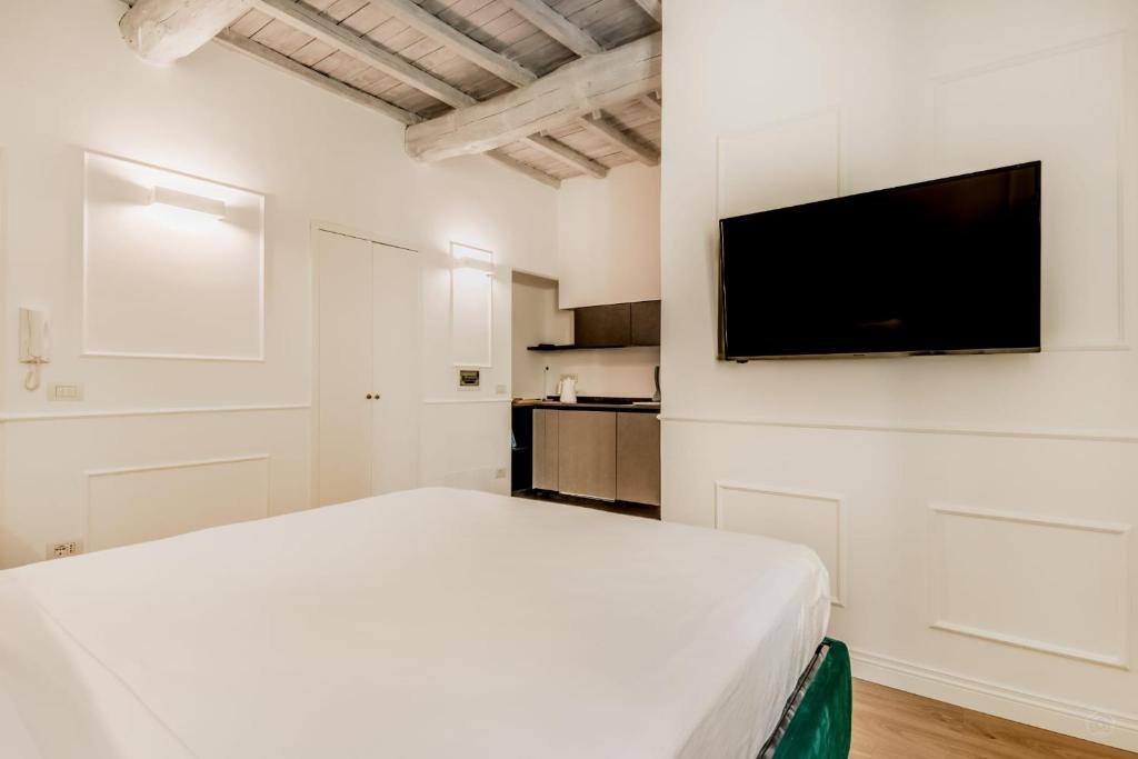a white bedroom with a bed and a flat screen tv at APT ROME - Vittoria Palace in Rome