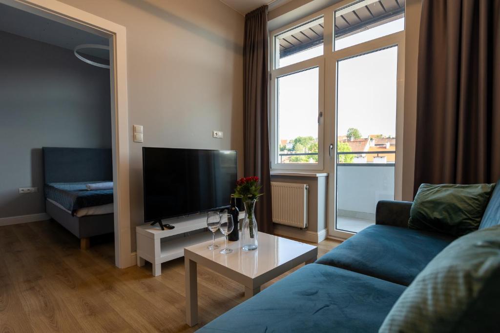 a living room with a blue couch and a tv at Ostróda City Center PKO lake apartments balcony in Ostróda