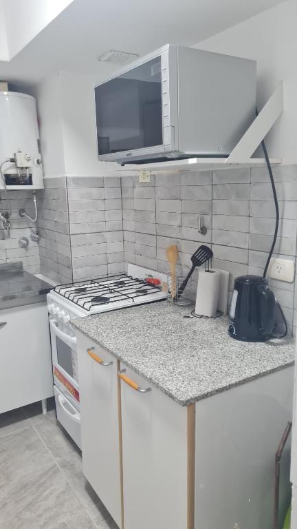 a white kitchen with a stove and a microwave at Departamento cómodo in La Rioja