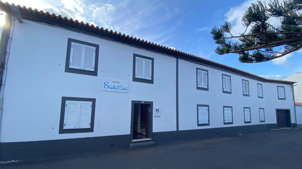 ein weißes Gebäude mit Fenstern und einer Tür in der Unterkunft Hotel Santa Cruz in Santa Cruz da Graciosa