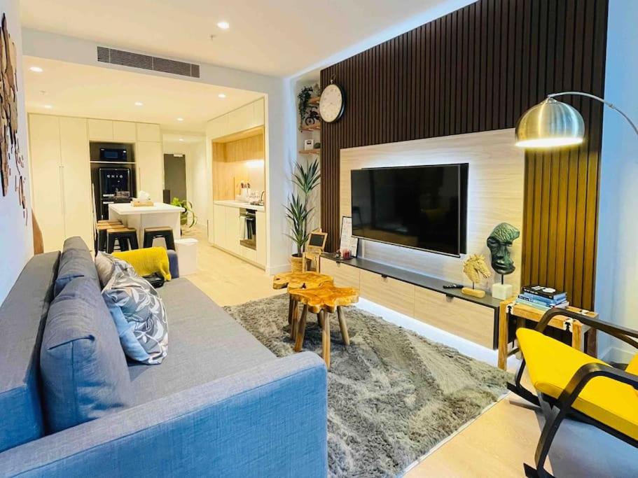 sala de estar con sofá azul y TV en 2Brooms Max for5 at Heart of CBD 1Free Parking en Melbourne