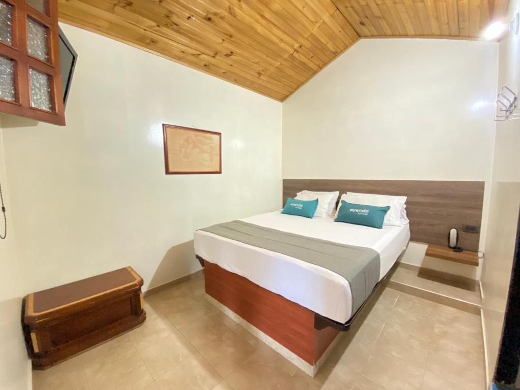 - une chambre avec un grand lit et des oreillers bleus dans l'établissement Ayenda Alfay Mosquera, à Mosquera