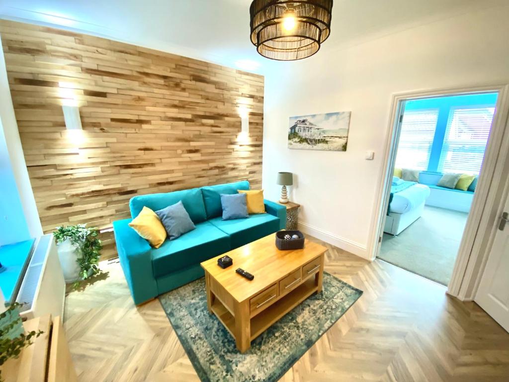 a living room with a blue couch and a wooden wall at The Beach House by Sorted Stay in Southend-on-Sea