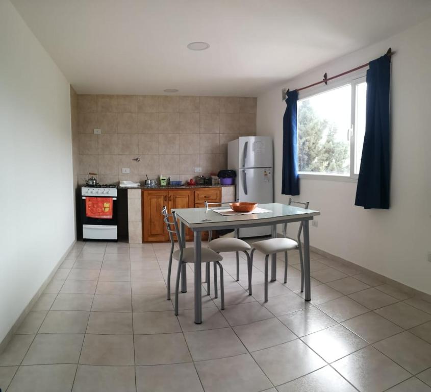 a kitchen with a table and chairs and a refrigerator at Departamento amplio y luminoso in Esquel