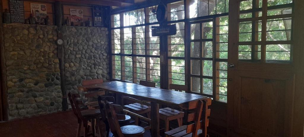 une table et des chaises dans une pièce avec fenêtres dans l'établissement Cabaña Altos de San Carlos, à Santa Marta