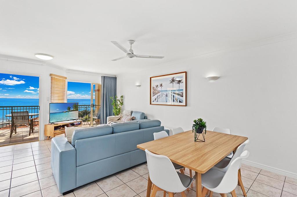 een woonkamer met een blauwe bank en een tafel bij Airlie Hasta Manana in Airlie Beach