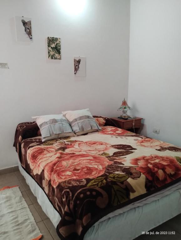 1 dormitorio con 1 cama con manta de flores en Casa para 6 con cochera-Maragus en Posadas