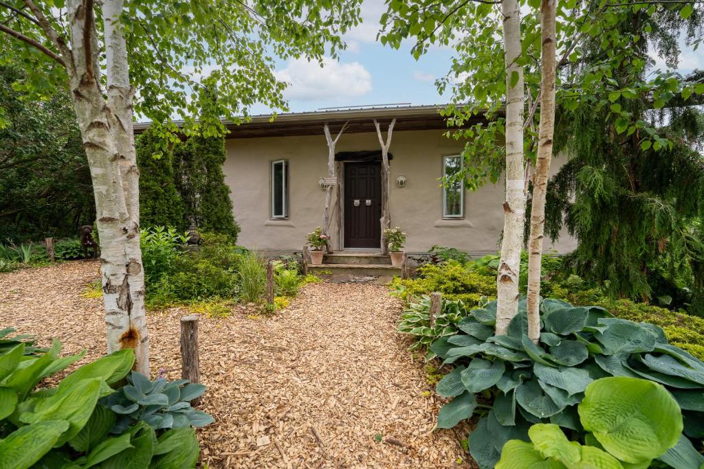 a house with a door in a garden with trees at Owl's Nest Suites in Carrying Place