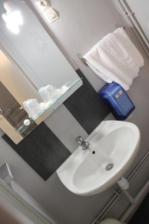 a bathroom with a white sink and a mirror at Hôtel De Normandie in Amiens