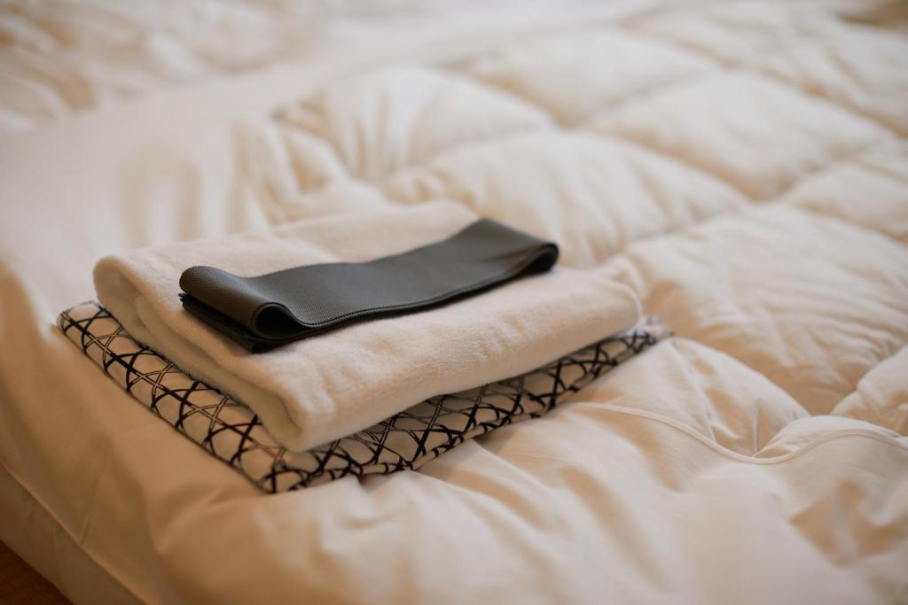 um livro preto em cima de uma cama branca em 芙蓉山居煙霞ー元富士の屋旅館ー em Fujikawaguchiko