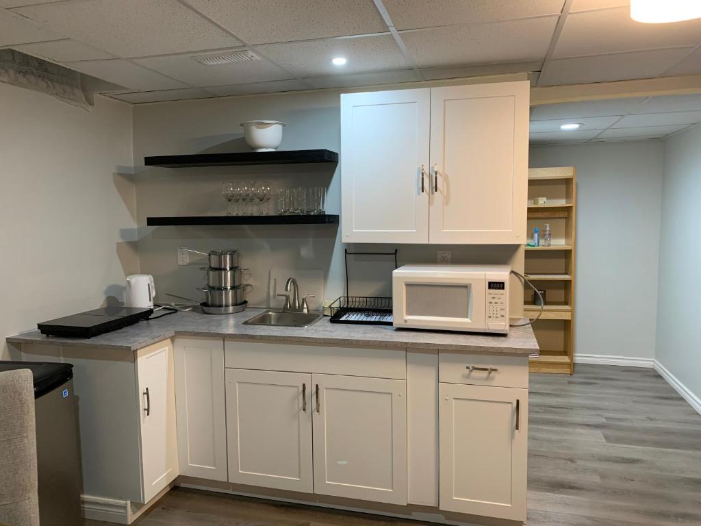 La cuisine est équipée de placards blancs et d'un four micro-ondes. dans l'établissement A Bright Specious 1 Bedroom Unit in the Basement, à Ottawa