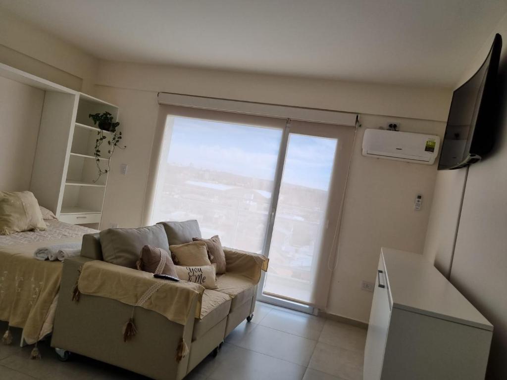 ein Wohnzimmer mit einem Sofa und einem großen Fenster in der Unterkunft Bella Vista in Cipolletti
