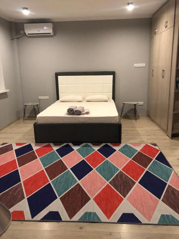 a bedroom with a bed and a colorful rug at Уютная квартира в центре города in Almaty