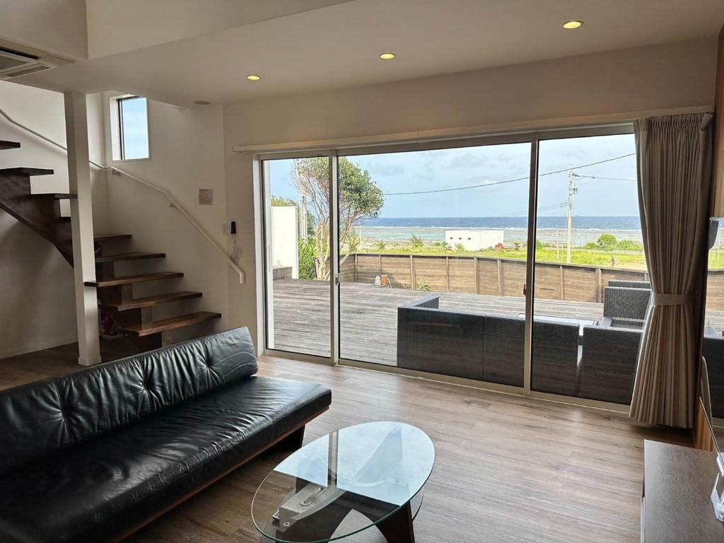 a living room with a black leather couch and a glass table at MAISON DE AILE - Vacation STAY 58600v in Amami