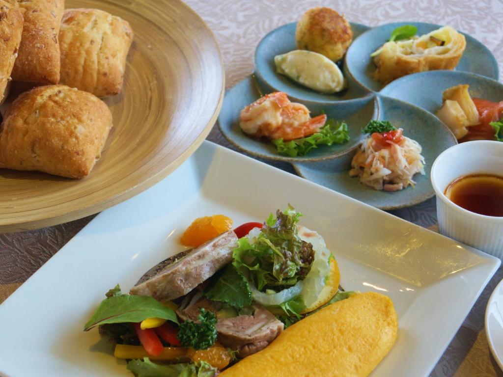 un plato de comida con un sándwich y otros alimentos en Tabist Nanki Shirahama Ryokan Mantei en Shirahama