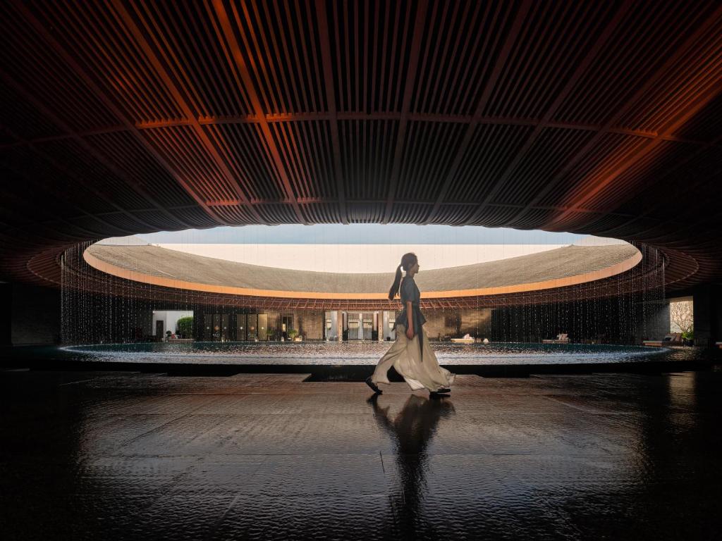 a woman walking in front of a building at Capella Tufu Bay, Hainan in Sanya