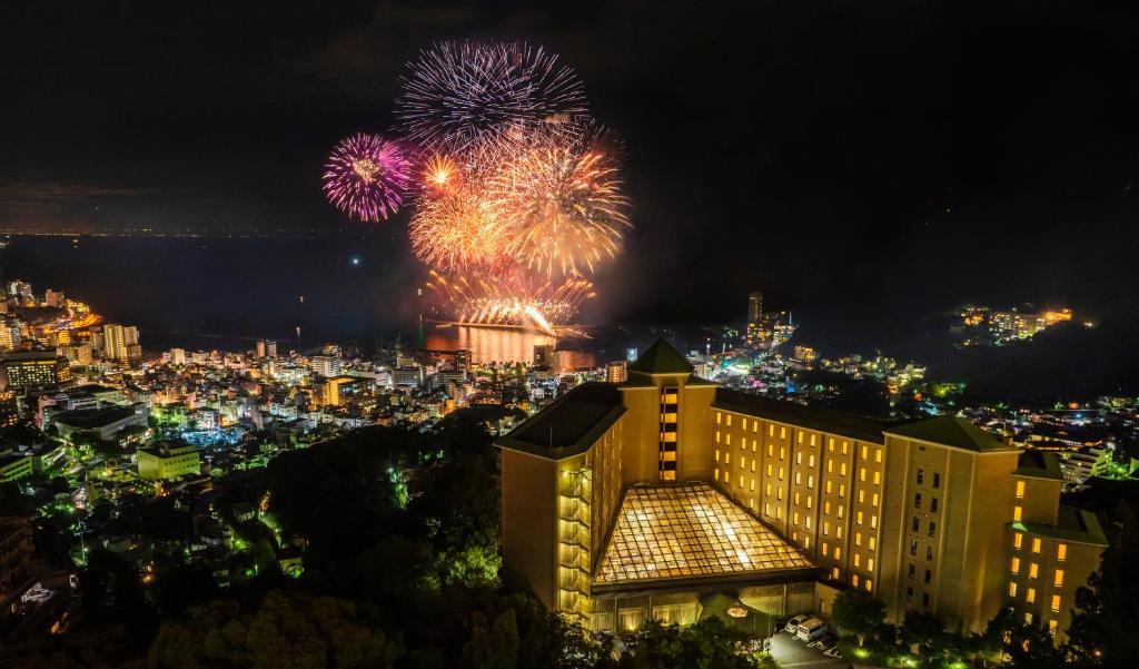 a view of a city with fireworks at night at KAMENOI HOTEL Atami in Atami