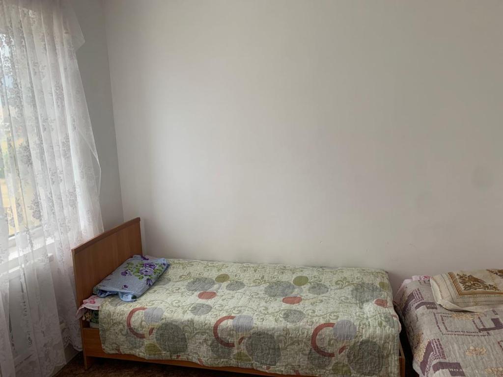 a small bedroom with a bed and a window at Guest House in Cholpon-Ata