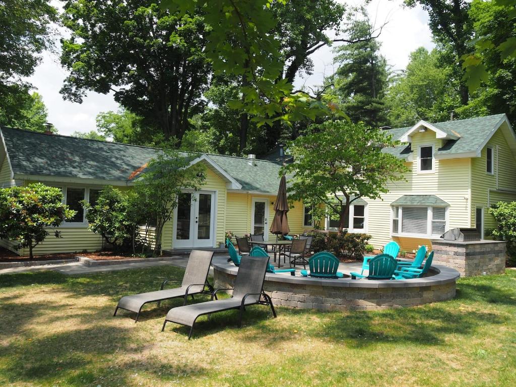 una casa amarilla con sillas y una piscina en el patio en Lorlee - A Large And Luxurious Lakefront Cottage!, en Woodland Beach