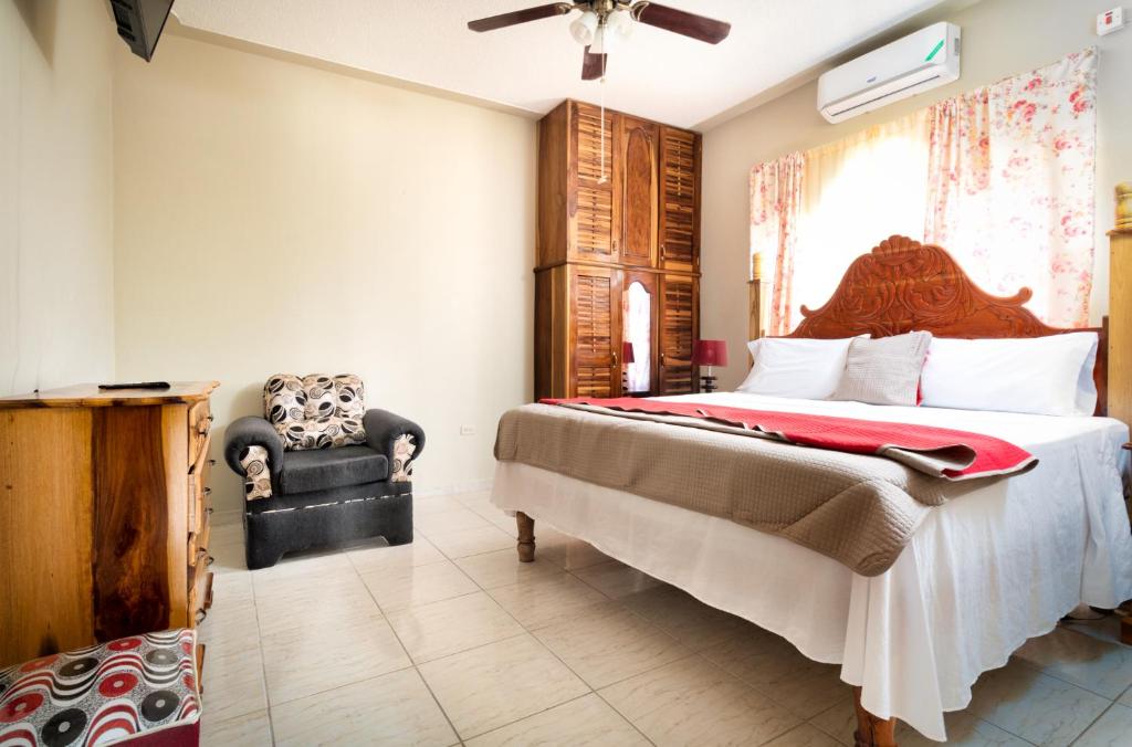 a bedroom with a large bed and a chair at Cozy Locale - Gold in Port Antonio