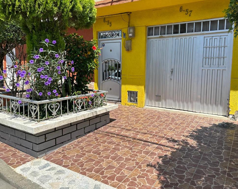 a yellow house with a garage with flowers in front of it at Las Camelias Apartahotel in La Virginia