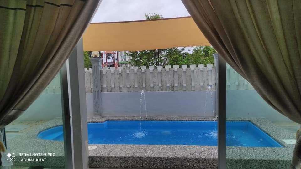 a view of a swimming pool from the window of a house at Murni Inn Pulasan in Guar Chempedak