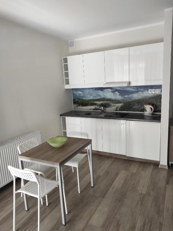 a kitchen with white cabinets and a wooden table and chairs at Private Baltic Cliff Niechorze obok Latarni Morskiej in Niechorze