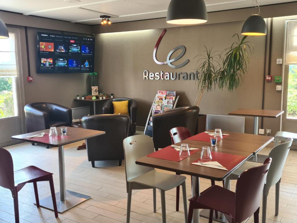 a restaurant with tables and chairs and a sign on the wall at Campanile Saint-Etienne Est- Saint-Chamond in Saint-Chamond