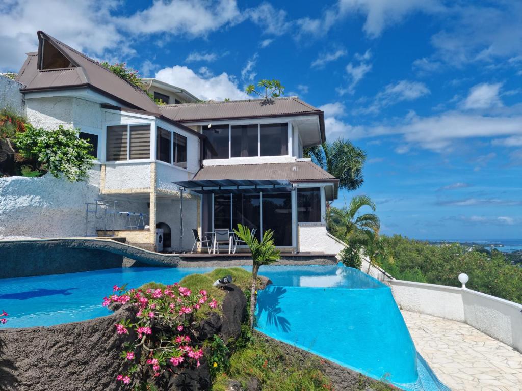 a house with a swimming pool next to the ocean at chez Karine et Robert in Punaauia