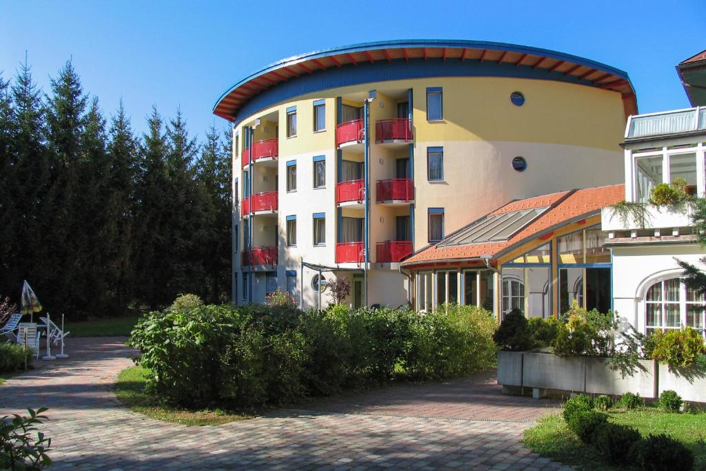 ein großes Gebäude mit roten Balkonen und einem Innenhof in der Unterkunft Hotel & Kurpension Weiss in Bad Tatzmannsdorf