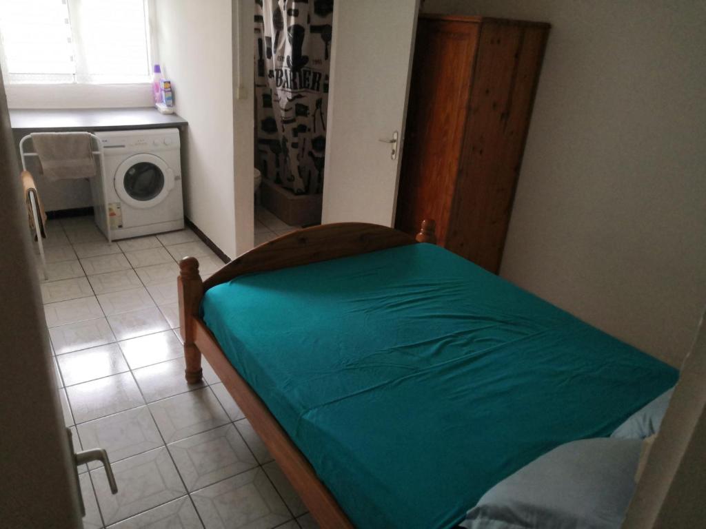 a small room with a bed with a green sheet at Appartement idéalement situé in Saint-Denis