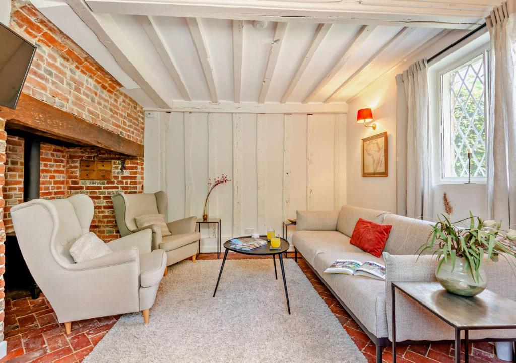 Corner Cottage - Kent في Benenden: غرفة معيشة مع أريكة وكراسي
