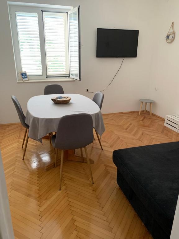 a room with a table and chairs and a flat screen tv at Beach House Murter in Murter