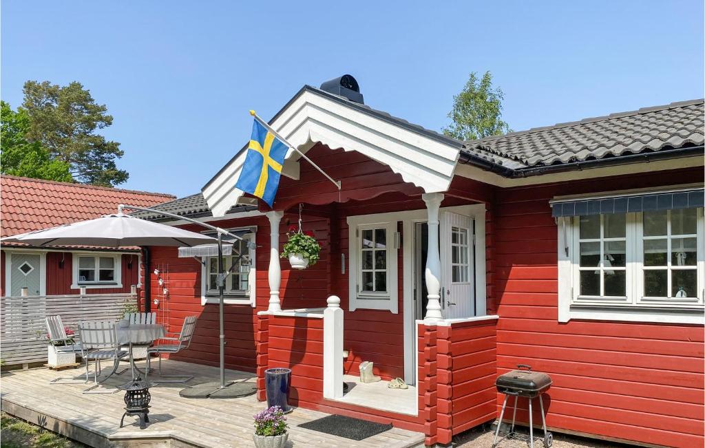 a red house with a flag on a deck at Gorgeous Home In Boxholm With House Sea View in Boxholm