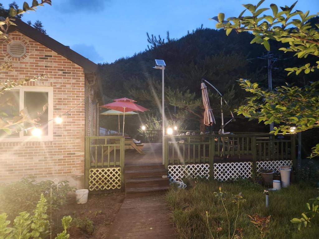 uma casa com um pátio e um guarda-chuva em Samhyeongjebonggil Pension em Gangneung