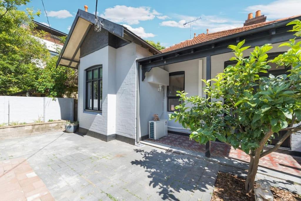 a white house with a tree in front of it at Crows Nest LemonTree Cozy 3 Bedroom House in Sydney